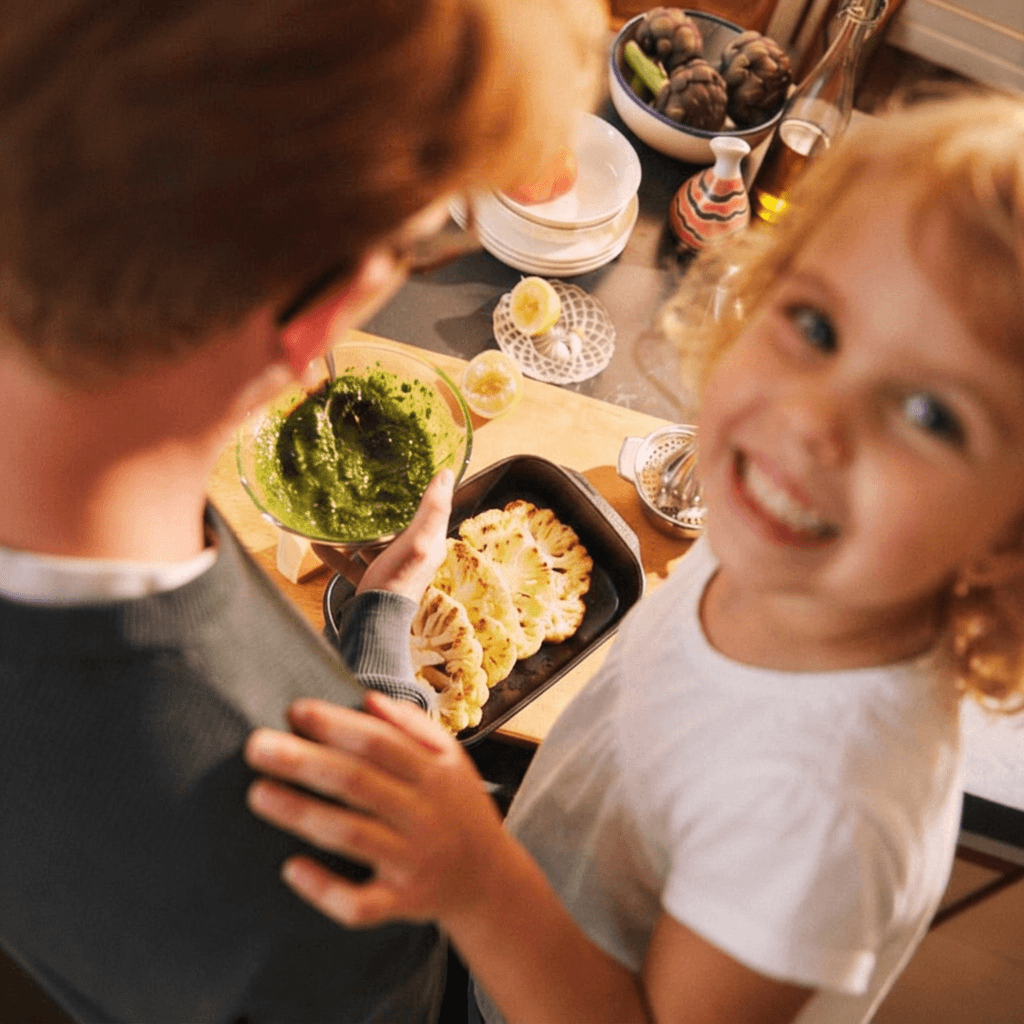 Adult i infant cuinant junts verdures a la cuina